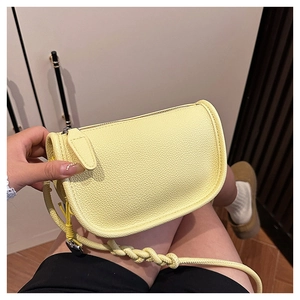 Détail du sac selle en cuir jaune à motif litchi avec bandoulière tressée à nœuds