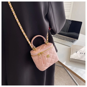 Detalle de mini bolso tipo cubo rosa acolchado con cadena y adorno de flor dorada