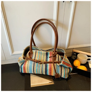 Detailed texture of colorful woven straw tote with brown leather handles and buckle