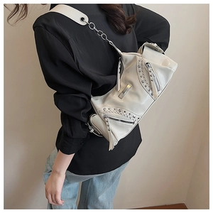 Détail du sac à bandoulière blanc cassé avec rivets argentés et texture brillante