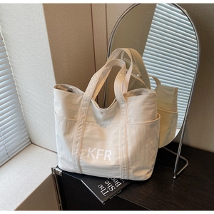 Detail of beige canvas tote bag showing side pocket, KFR print and snap closure