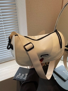 White nylon half-moon crossbody bag with adjustable strap and brand logo shown in home setting