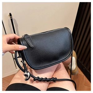 Détail du sac selle en cuir grainé noir avec bandoulière tressée et pendentif argent