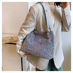 Close-up of sparkling sequin tote bag with light blue leather strap and gold ring details