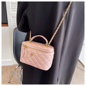 Detalle del bolso de caja rosa acolchado con camelia y cadena usado por una modelo