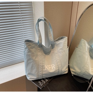 Detail view of large mint green canvas tote bag with side pockets and white KFR lettering