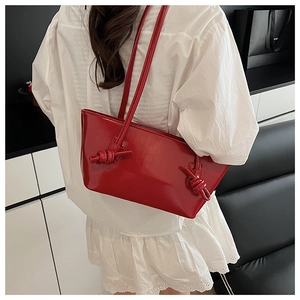 Détail du sac à épaule en cuir verni rouge brillant avec design de nœud décoratif