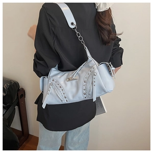 Détail d'un sac à bandoulière bleu clair avec rivets argentés et chaîne en métal