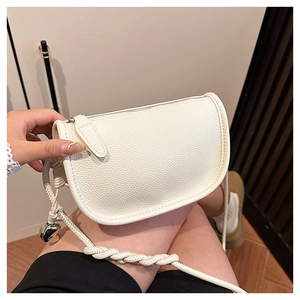 Détail du sac selle en cuir litchi blanc avec bandoulière tressée et ornement en métal