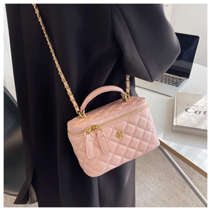 Detalle de bolso tipo cubo acolchado rosa con logo de flor dorada y asa de cadena