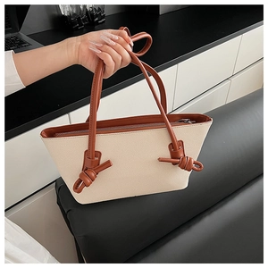 Détail du sac cabas tissé avec poignées en cuir marron et grands nœuds décoratifs