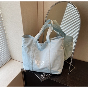 Detail of light blue canvas tote bag with outer pockets and white KFR logo branding