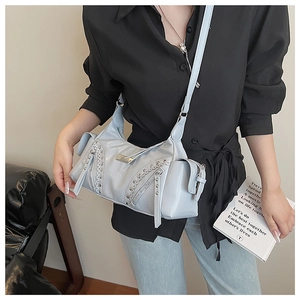 Détail du sac bandoulière bleu clair avec rivets métalliques et zip sur un mannequin