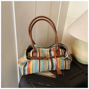 Close-up of colorful striped straw tote bag featuring brown leather handles and buckles