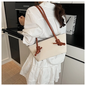 Détail du grand sac cabas crème avec bandoulière marron nouée porté par un modèle