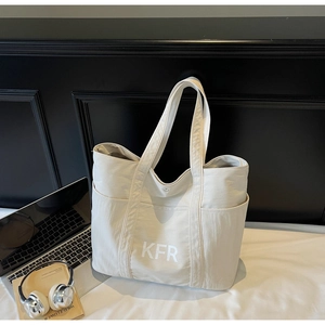 Detail of a large beige canvas tote bag with KFR print and side pockets for commuting