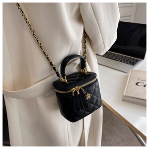 Detalle de bolso cubo acolchado negro con cadena y colgante de camelia