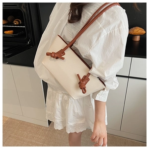 Détail du sac cabas en toile avec lanières en cuir marron et nœuds décoratifs