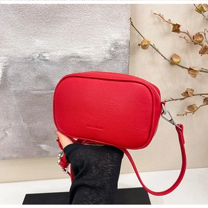 Dettaglio della borsa a tracolla rossa in pelle martellata con logo e gancio in metallo