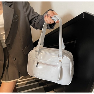 Macro detail of embossed lettering on a light grey glossy shoulder bag with silver zipper