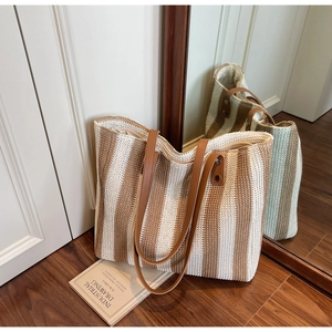 Detail of striped woven tote bag with brown leather straps and secure zipper closure