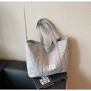 Detail of grey canvas tote bag with white KFR logo and side pockets on a sofa