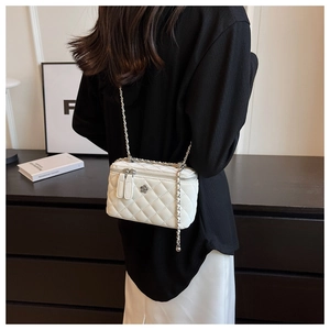 Detail of white quilted crossbody bag with silver floral buckle and metal chain strap