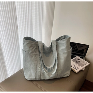 Light blue canvas tote bag featuring double handles and side pockets in a lifestyle setting