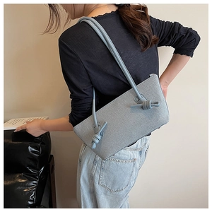 Détail d'un sac bandoulière bleu clair avec un design minimaliste à brides nouées