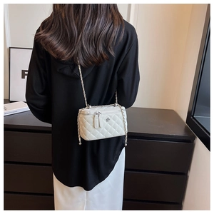 Detail der weißen gesteppten Mini-Box-Tasche mit goldener Kette an einem weiblichen Model
