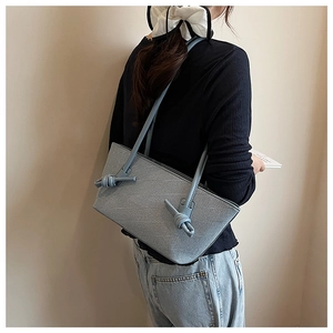 Détail du sac cabas bleu clair montrant le nœud sur la bandoulière et le cuir texturé