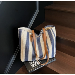Detailed view of blue and beige woven tote bag featuring brown leather shoulder straps
