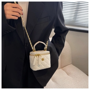 Detalle del bolso de cubo acolchado blanco con cadena dorada y adorno de camelia