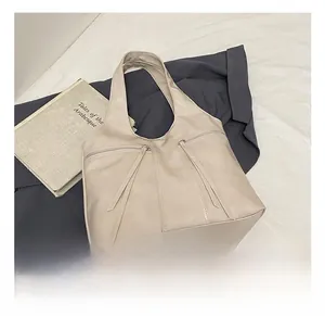 Détail du grand cabas en cuir beige avec fermetures éclair à pompons et design épuré