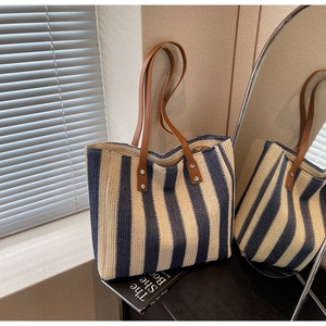 Detail of blue and white striped woven straw tote bag with brown leather handles