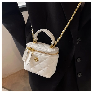Detalle de mini bolso bombonera blanco acolchado con cadena dorada y colgante de flor