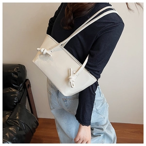 Détail d'un sac cabas blanc lisse avec des décorations de bandoulière nouées