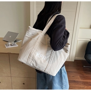 Detail of a large cream canvas tote bag with KFR lettering and side utility pockets