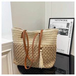 Detail of bicolor woven tote bag featuring leather handles and decorative wood bead tassel