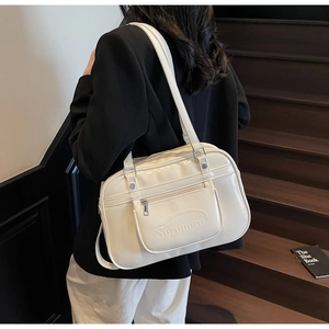 Close-up of cream white PU leather tote bag worn as an underarm bag by a female model