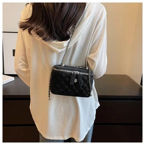 Detail einer schwarzen gesteppten Vanity-Tasche mit Silberkette, getragen vom Model