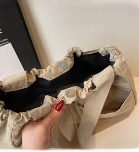Close-up of beige shoulder bag interior featuring magnetic snap and glossy metal hardware