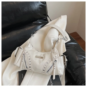 Détail du sac hobo crème avec rivets argentés et finition brillante sur tissu blanc