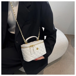 Detalle de bolso cubo blanco acolchado con cierre de camelia dorada y asa de cadena