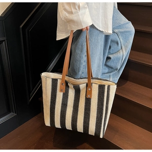 Close-up of a striped woven tote bag featuring brown leather handles and metal rivets