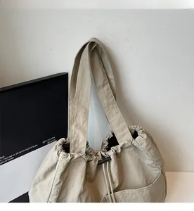 Detail of khaki nylon tote bag featuring wide reinforced handles and drawstring closure