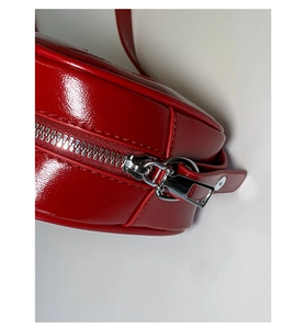 Close-up of silver metal zipper and stitching on red glossy PU leather bucket bag