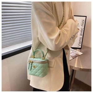 Detalle del mini bolso tipo cubo verde menta acolchado con cadena dorada y herraje floral