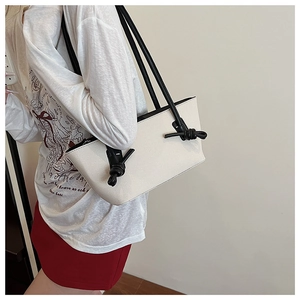 Détail du grand sac cabas blanc tissé avec bandoulière noire à nœuds et design minimaliste