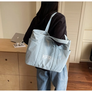 Close-up of light blue canvas tote bag featuring side pockets and KFR logo detail